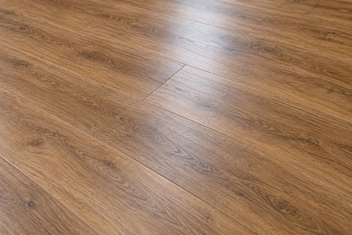 Close-up of warm brown oak-look laminate planks with visible grain and staggered joints.