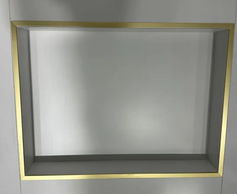 A rectangular recessed niche with gold-colored edge trim in a pale tiled wall.