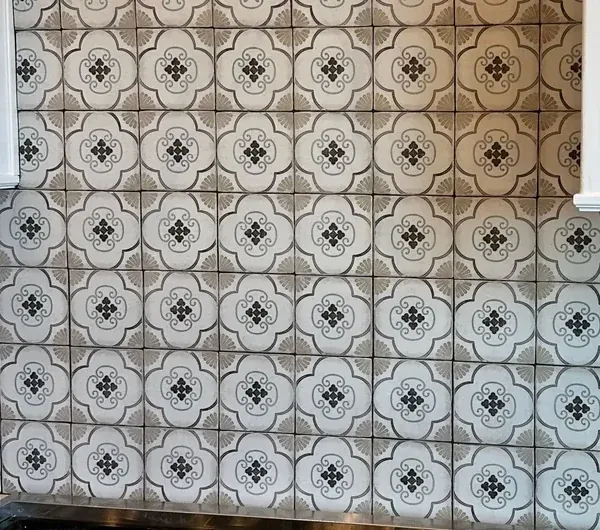 A close view of black, gray and cream patterned tiles above the upper edge of a kitchen range.