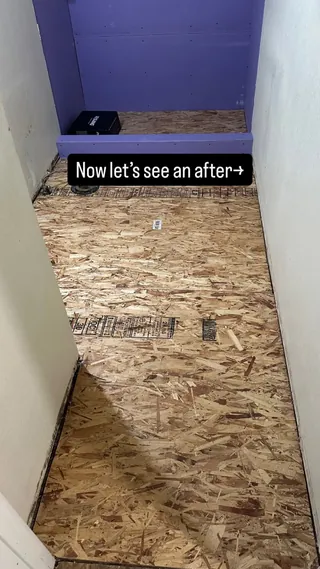 Wood-based subfloor and exposed purple wall boards before the shower tile installation.