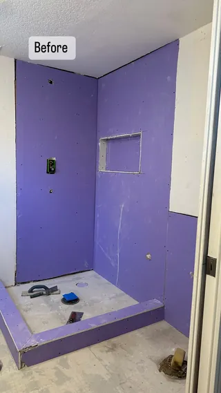 Shower at a purple wall-board preparation stage, with a recessed niche opening and raised threshold before wall tile.