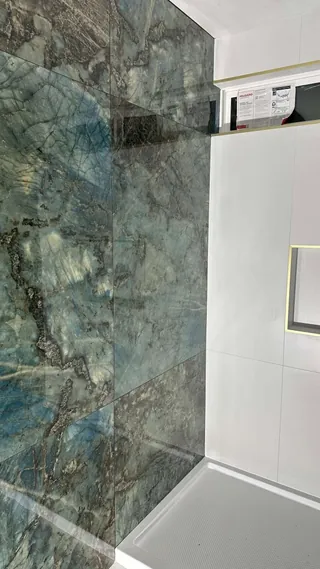 Blue-green veined rectangular wall tile beside a high horizontal window and white shower wall.