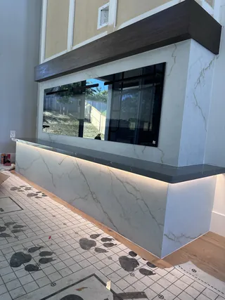 Pale veined fireplace surround and raised base beneath a dark mantel, with warm lighting below the dark hearth ledge.