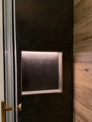 Illuminated recessed niche in a charcoal tiled shower wall
