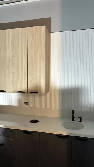 Vertical ribbed backsplash beside a wood-tone cabinet and round sink